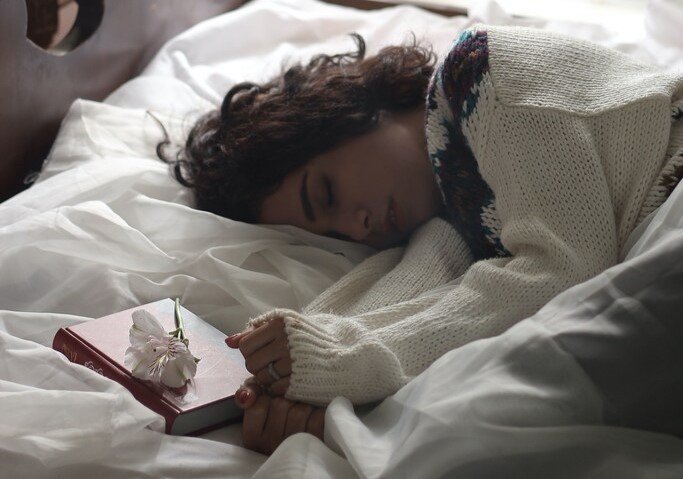 Mulher adormecida ao lado de livro e flor Às 3 da manhã, o silêncio revela mistérios espirituais que ecoam na tranquilidade da noite.